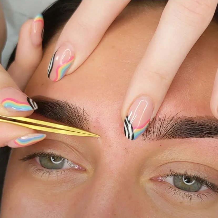 Abbie mapping a client’s brows with gold tweezers
